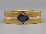 gros plan d'une bague en or avec un saphir et des diamants