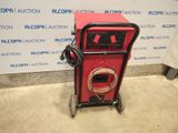 a red machine sitting on top of a cement floor next to a wall