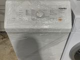 une machine à laver blanche posée à côté d'une pile de cartons