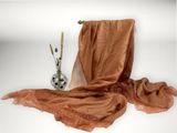 a brown scarf on a table next to a vase with flowers