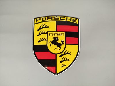 un gros plan sur l'emblème d'une Porsche sur un mur blanc