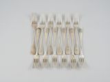 six fourchettes posées sur une table blanche