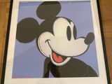 a framed mickey mouse painting on a wooden floor with a red frame