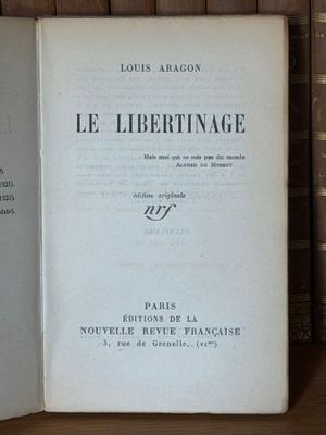un vieux livre posé sur une étagère en bois, à côté d'une pile de livres