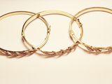 three gold bang bracelets on a white background with a price tag