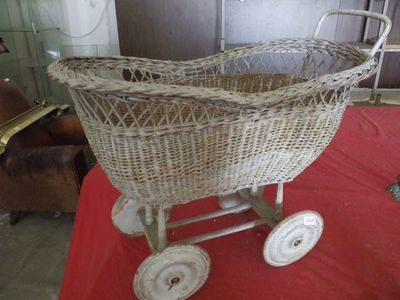 a wicker baby stroller on a red table