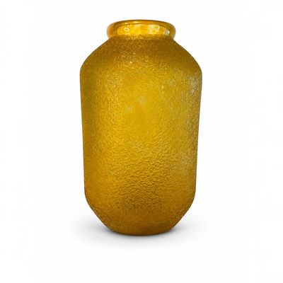 un vase en verre jaune posé sur une surface blanche