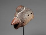 a wooden mask on a stand with a gray background