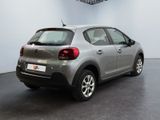the back of a silver car in a room with a black floor