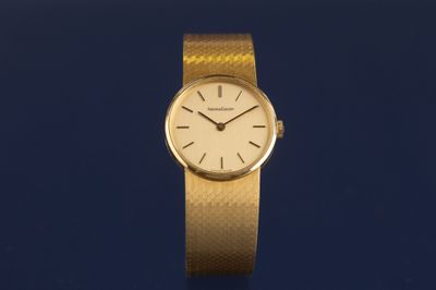 a close up of a gold wrist watch on a blue surface