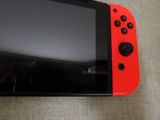 a red and black nintendo wii game controller sitting on a couch