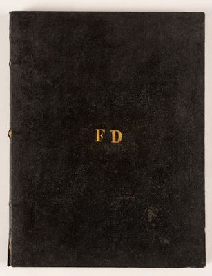 un livre noir orné de lettres dorées, posé sur une surface blanche