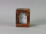 une petite horloge en bois avec un cadran blanc posée sur une table