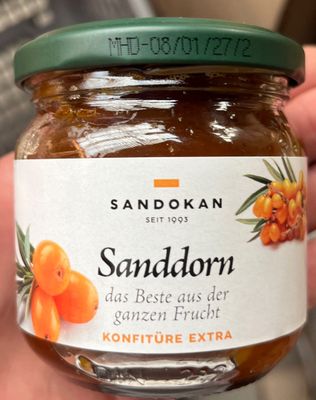 quelqu'un tient un pot de confiture contenant des oranges