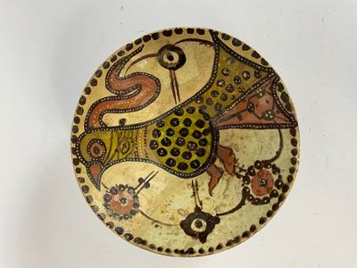 a decorative bowl with a bird on it on a white surface