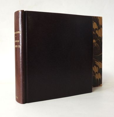 un vieux livre à la couverture marron posé sur une table blanche