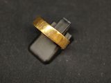 gros plan d'une bague en or sur une surface noire