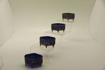 trois bols en verre bleu posés sur des socles en acrylique transparent