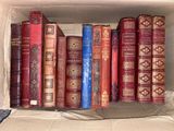 a box full of old books on a bed