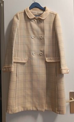 un manteau beige accroché au mur d'une pièce dont la porte est ouverte