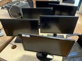 three computer monitors sitting on a desk in a room
