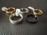 four different types of wedding rings on a black leather surface