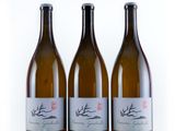 three bottles of wine sitting next to each other on a white surface