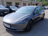 Une Tesla Model 3 garée sur un parking, avec d'autres voitures en arrière-plan