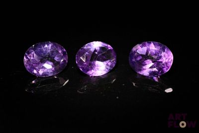 trois améthystes violettes posées sur une surface noire
