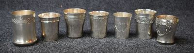 six vases en argent sont alignés sur une surface noire
