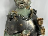 a statue of a man sitting on a rock with a candle