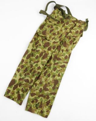 un gros plan sur un pantalon de camouflage posé sur une surface blanche