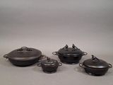 four pieces of cast iron pots and pans sitting on a table