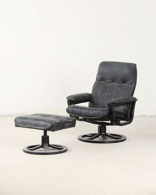 un fauteuil inclinable en cuir noir et un repose-pieds dans une pièce blanche