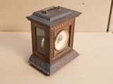 a small clock sitting on a table in front of a cardboard box
