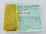 yellow bar of gold sitting on top of a piece of paper next to a receipt