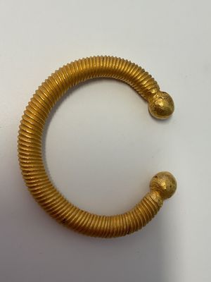 une image d'un bracelet en or sur une surface blanche