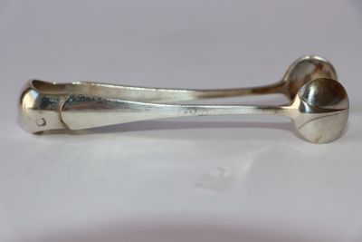 une cuillère en argent et un repose-cuillère posés sur une surface blanche