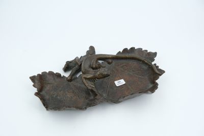 a metal object with a lizard on it on a white surface