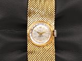 a close up of a gold wrist watch on a black cushion