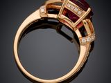 a close up of a gold ring with a red stone and diamonds