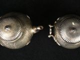 pair of antique silver plated teapots on black background