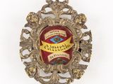une image représentant une broche rouge et dorée entourée d'un ruban