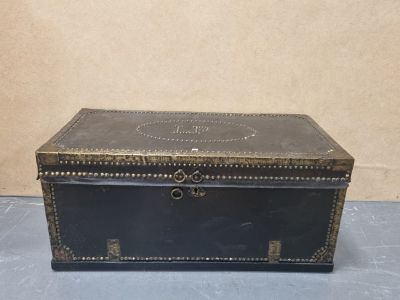 an old black leather trunk with brass hardware on the top