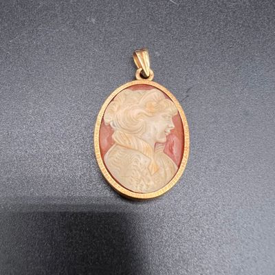 un gros plan d'un pendentif plaqué or représentant le profil d'une femme