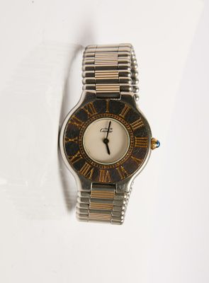 une montre-bracelet argentée et dorée posée sur une surface blanche