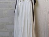a white dress hanging on a clothes rack next to a brick wall