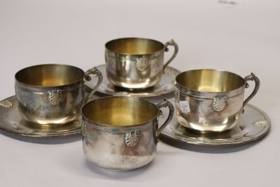 four silver cups and saucers sitting on top of a white table