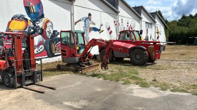 trois chariots élévateurs garés devant un bâtiment orné d'une fresque murale sur l'un de ses côtés