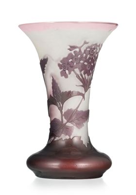 a glass vase with purple flowers on it on a white surface